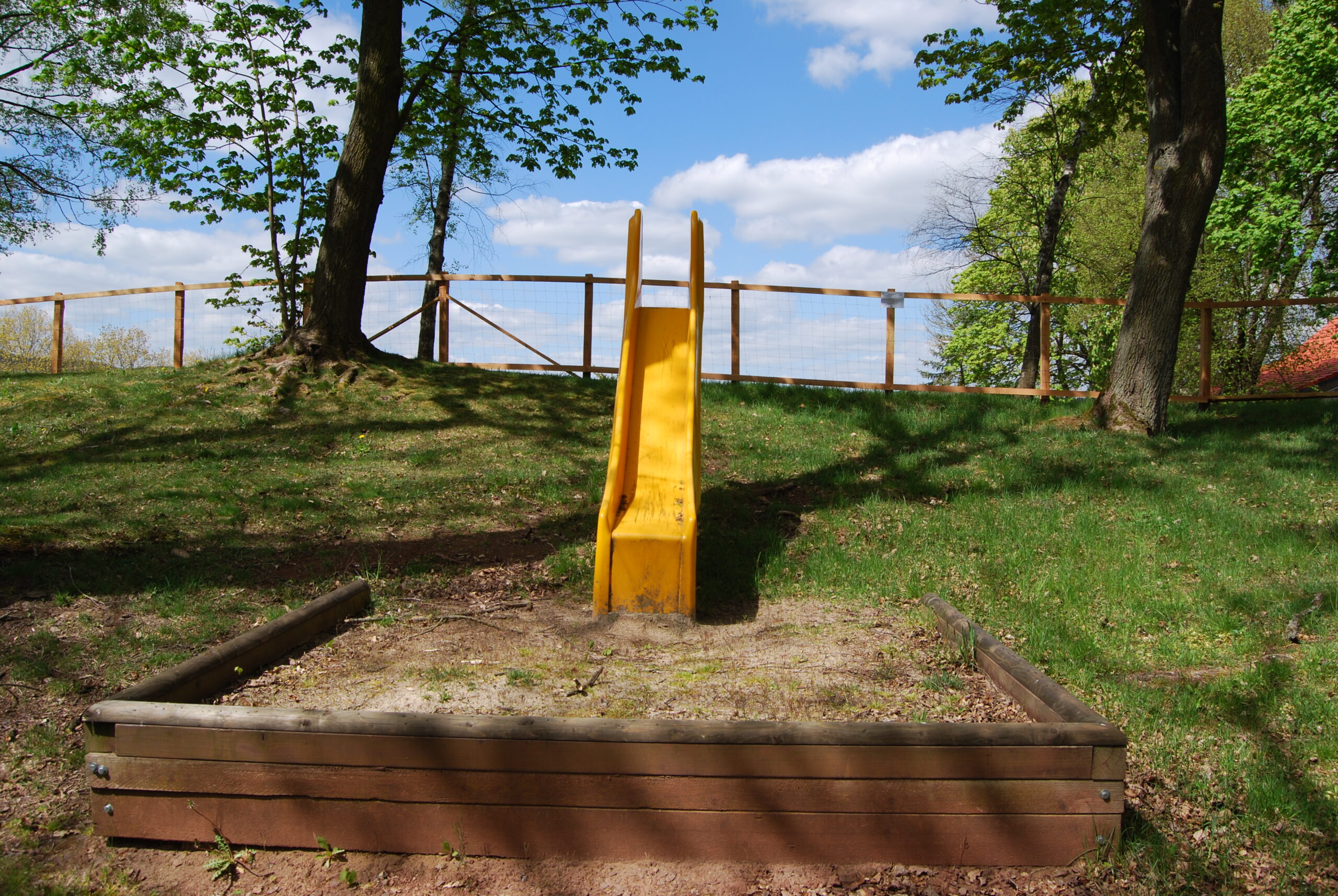 Eine gelbe Rutsche steht auf einem Spielplatz in Adorf. Die Rutsche ist von Bäumen umgeben, die den Spielplatz mit grünem Laub einrahmen. Die Umgebung wirkt ruhig und naturnah. Eine gelbe Rutsche steht auf einem Spielplatz in Adorf. Die Rutsche ist von Bäumen umgeben, die den Spielplatz mit grünem Laub einrahmen. Die Umgebung wirkt ruhig und naturnah.