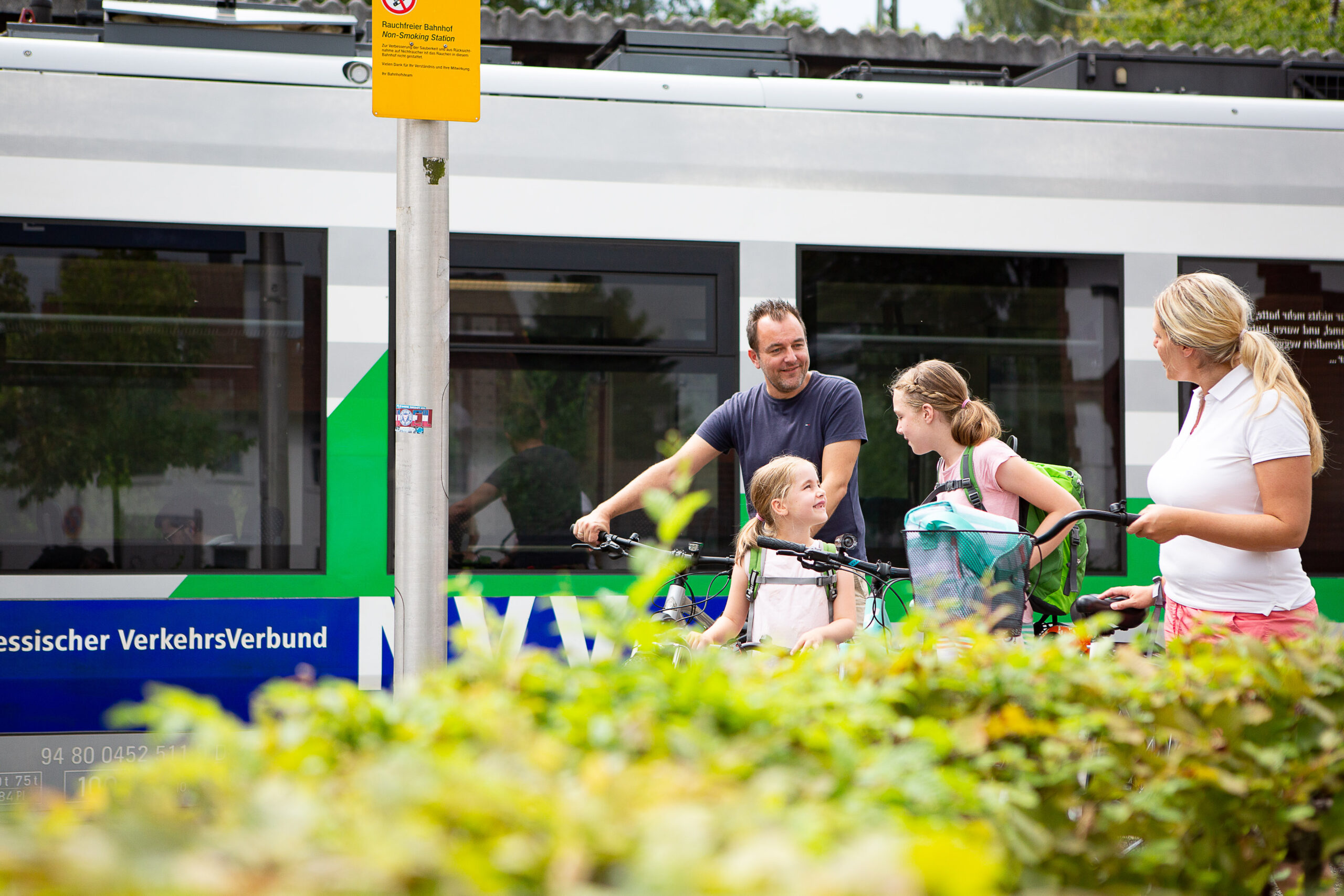 Das Bild zeigt eine Familie mit Fahrrädern, die vor einem Zug steht – vermutlich an einem Haltepunkt in der Nähe des Diemelsees. Die Szene zeigt die Verbindung von Radfahren und öffentlichem Nahverkehr (ÖPNV) und macht deutlich, wie nachhaltig und flexibel Ausflüge in der Region gestaltet werden können. Die Bahn ist im Hintergrund zu erkennen.